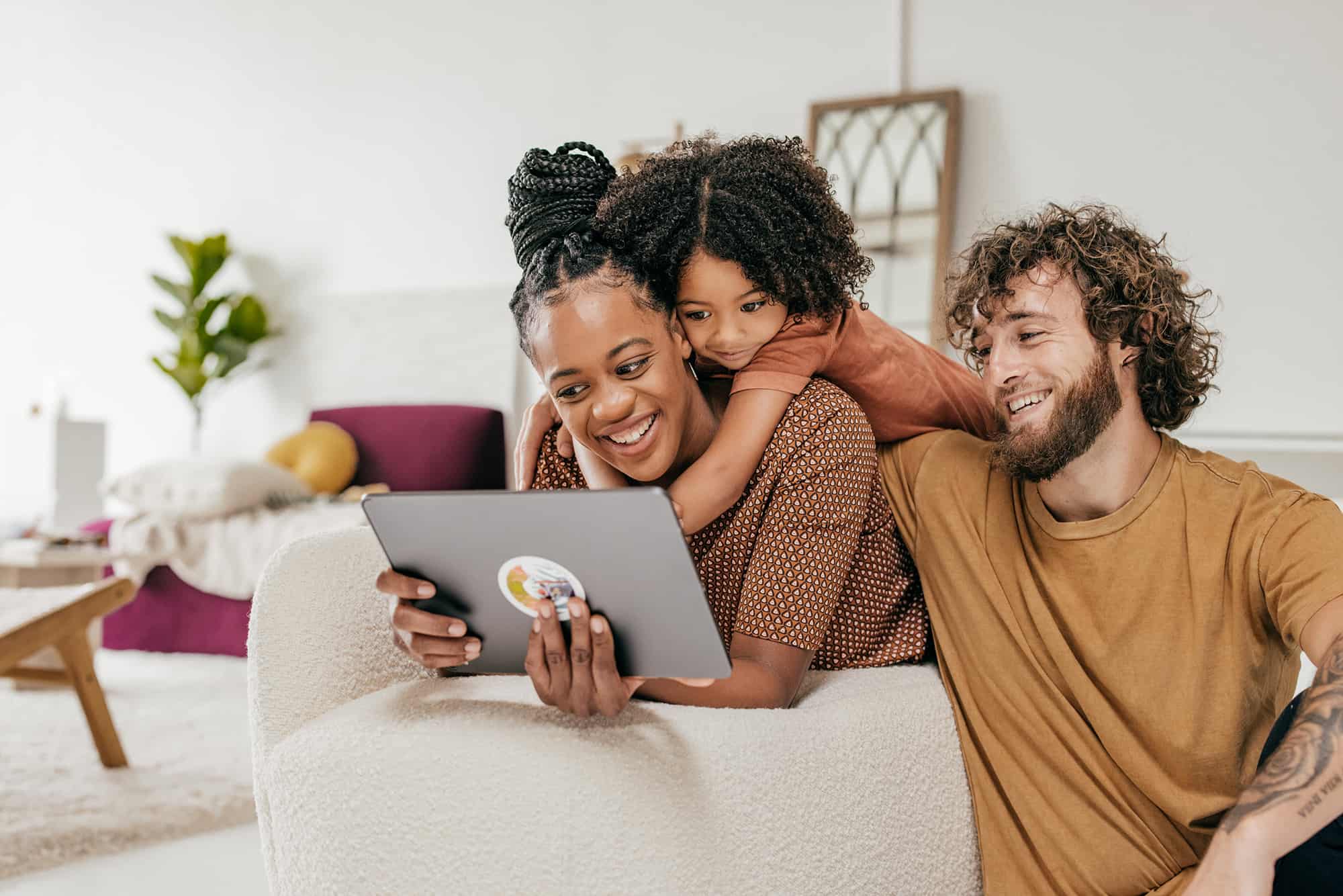Smiling parents and daughter at home watching online movie together