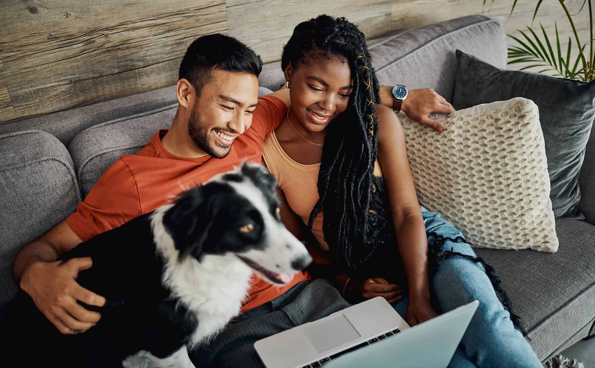young couple sitting with their Border Collie in their living room at home