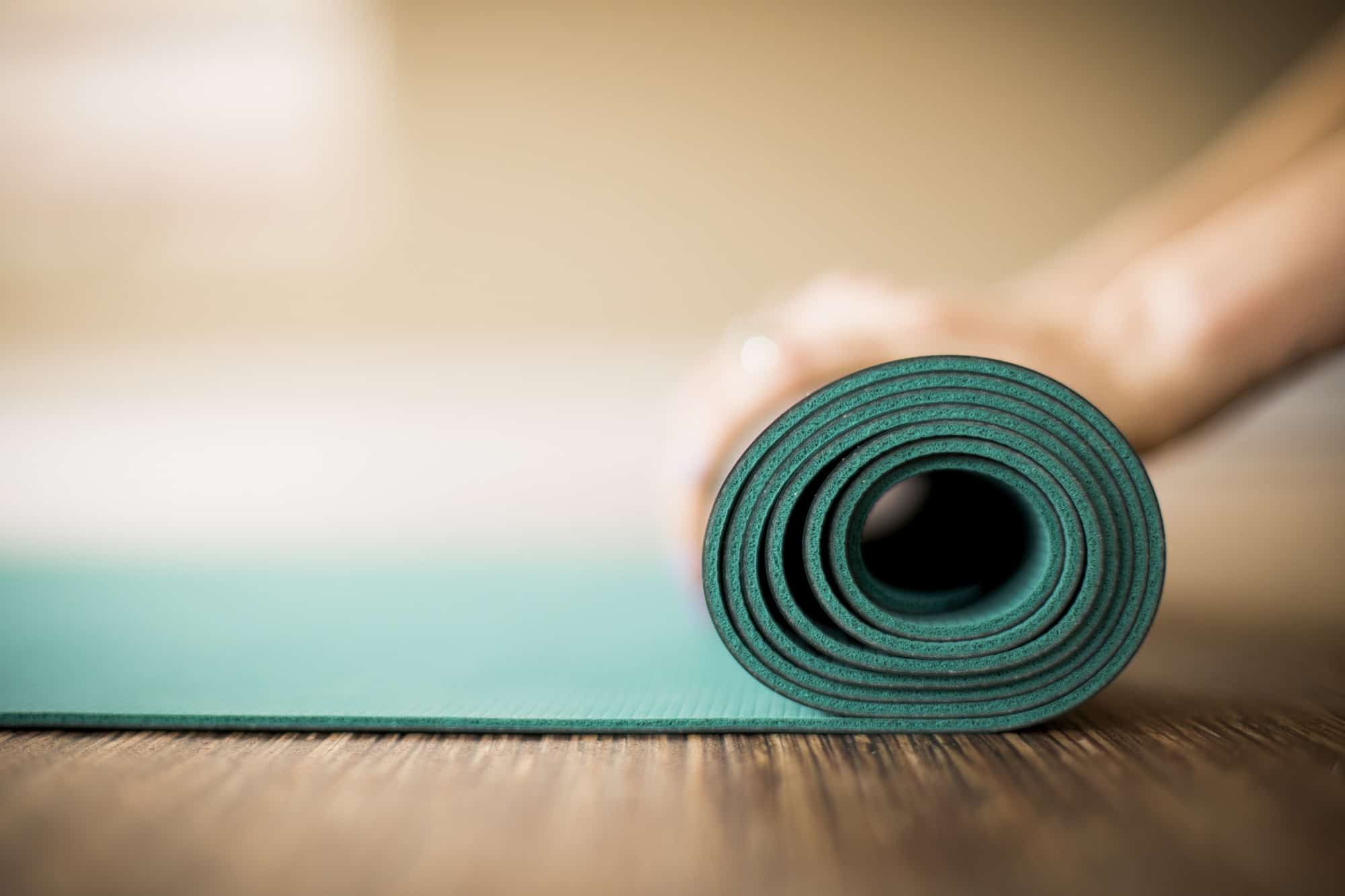 Woman rolling up yoga mat.